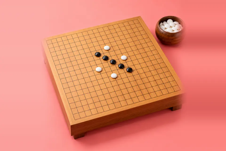 Five black stones in a diagonal line on a gridded board, coral backdrop